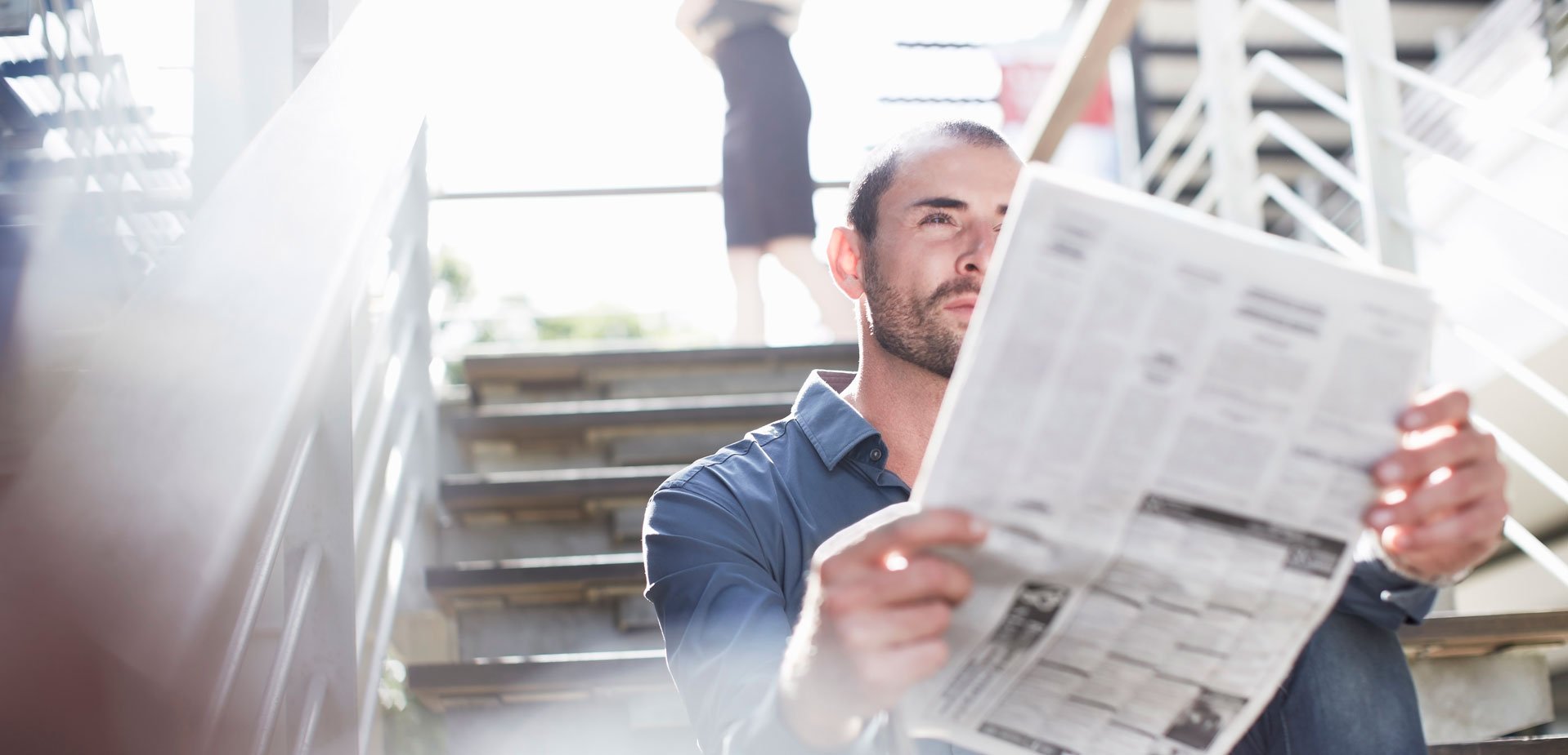 Ein Mann der auf einer Treppe sitzt und Zeitung liest