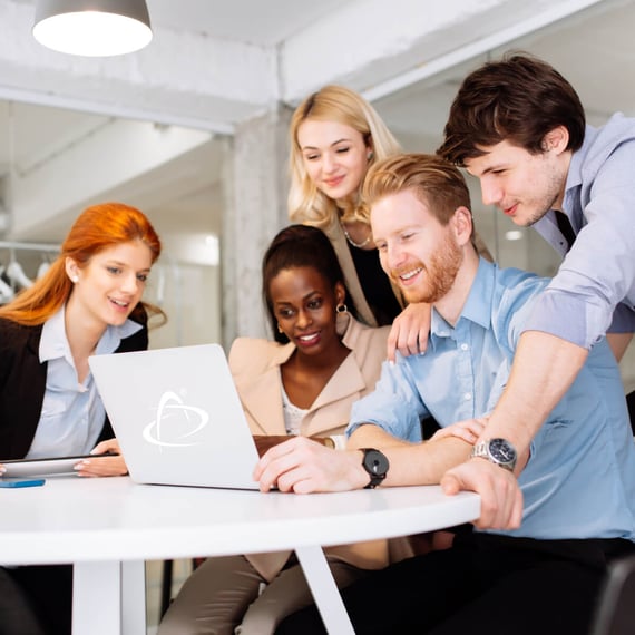 Fünf junge Berufstätige sitzen lächelnd um einen Laptop herum und arbeiten in einer modernen Büroumgebung zusammen | social-media-marketing strategien SUNZINET