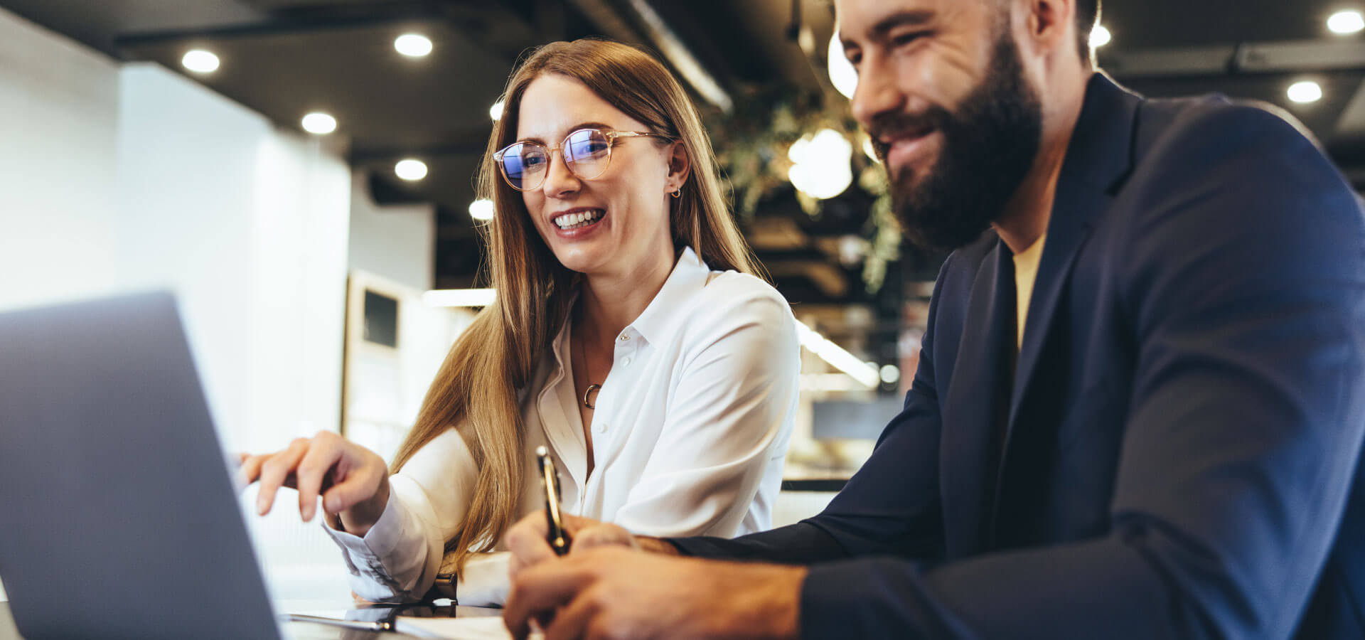 a woman and a man sit at one laptop and take notes-SUNZINET