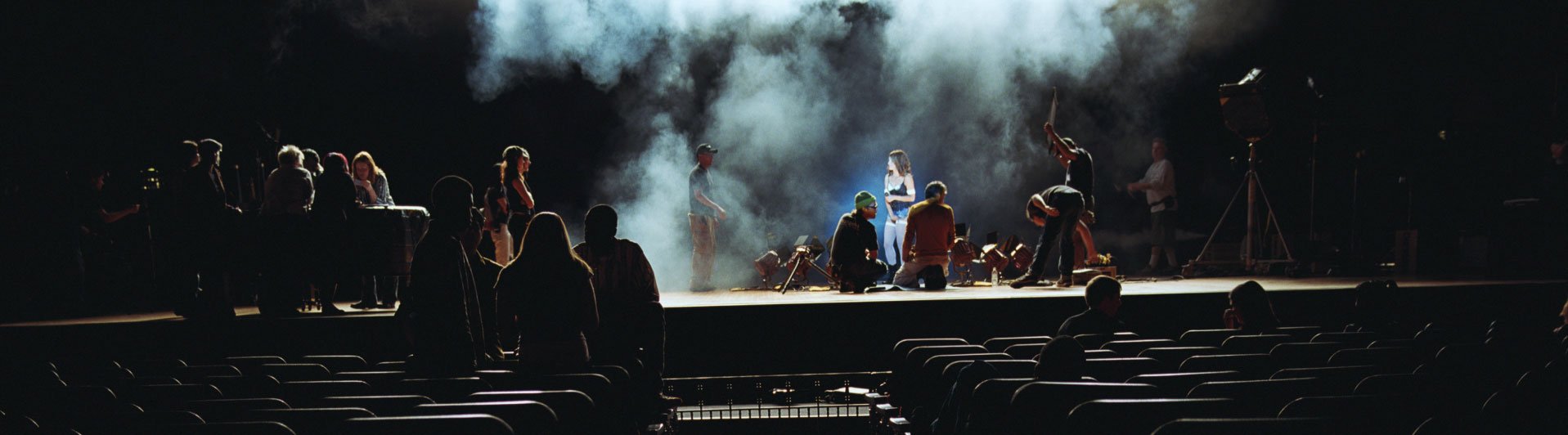 Schauspieler auf einer Bühne mit einer Frau und einem Mann im Rampenlicht und Zuschauern