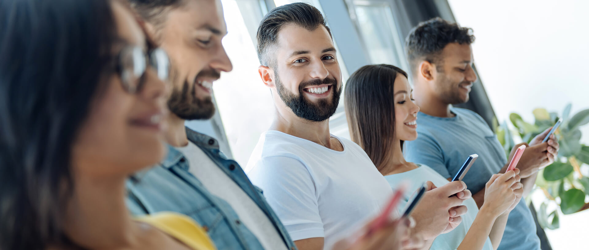 Mehrere Personen, darunter Frauen und Männer, die ein Smartphone in der Hand halten - Intranet Implementierung von SUNZINET