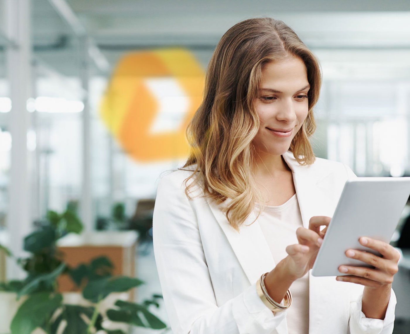 Eine braunhaarige Frau schaut lächelnd auf ein Tablet. Beezy Logo.