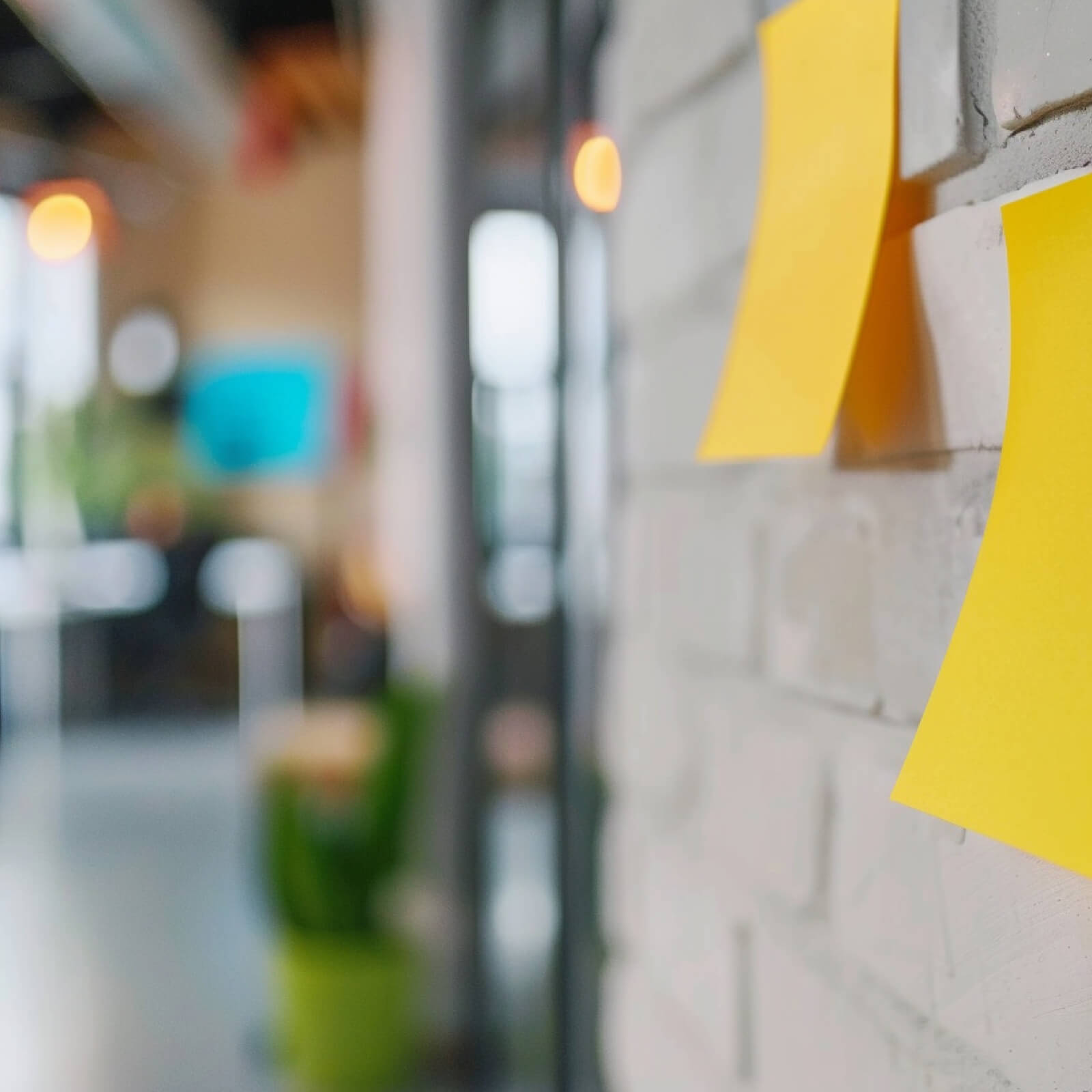 Close-up of a white brick wall with yellow sticky notes on it. | Market entry framework SUNZINET