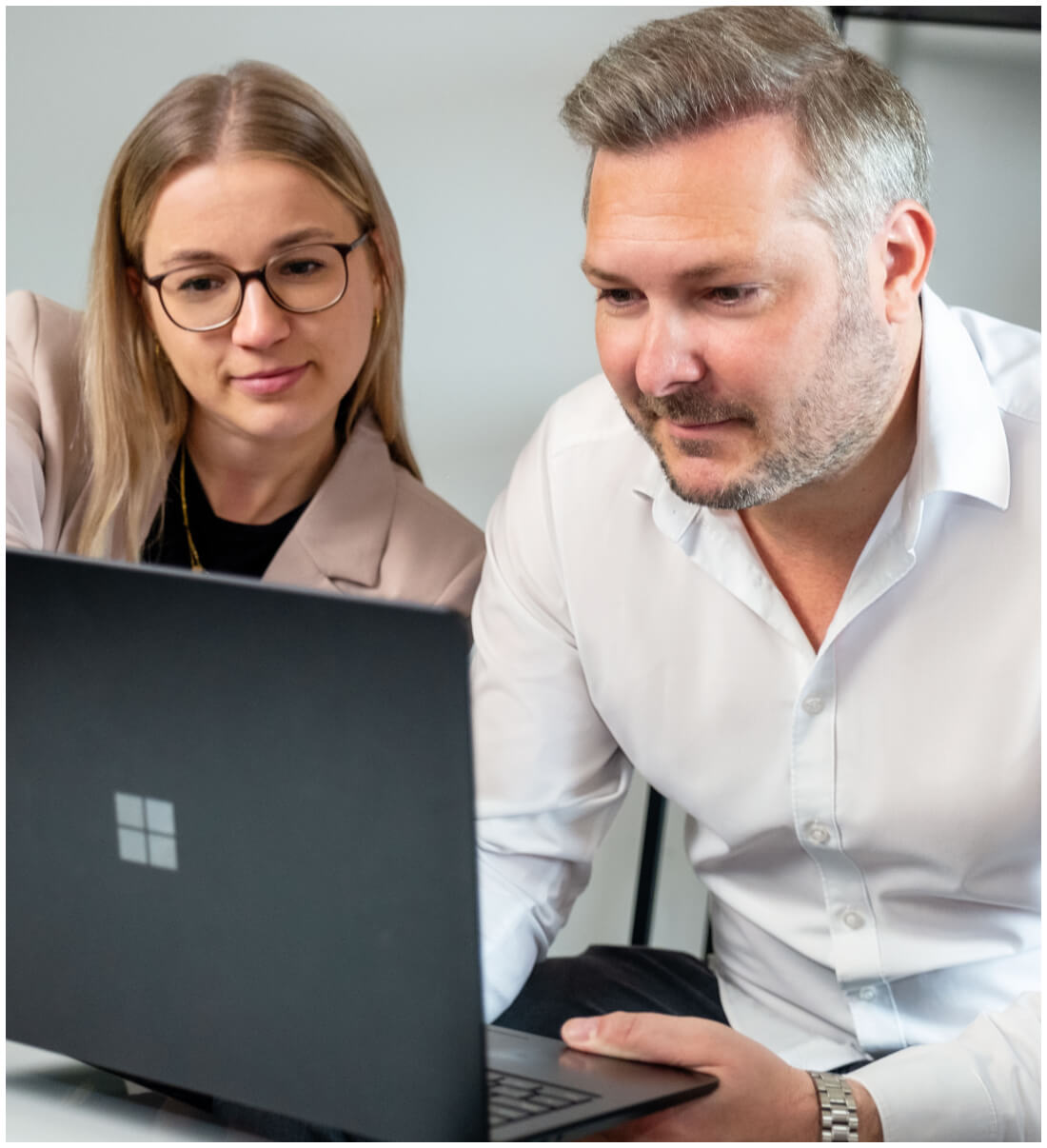 A man and a woman, sitting next to each other and looking at Laptop: Agency for Systemintegration & Process Automation