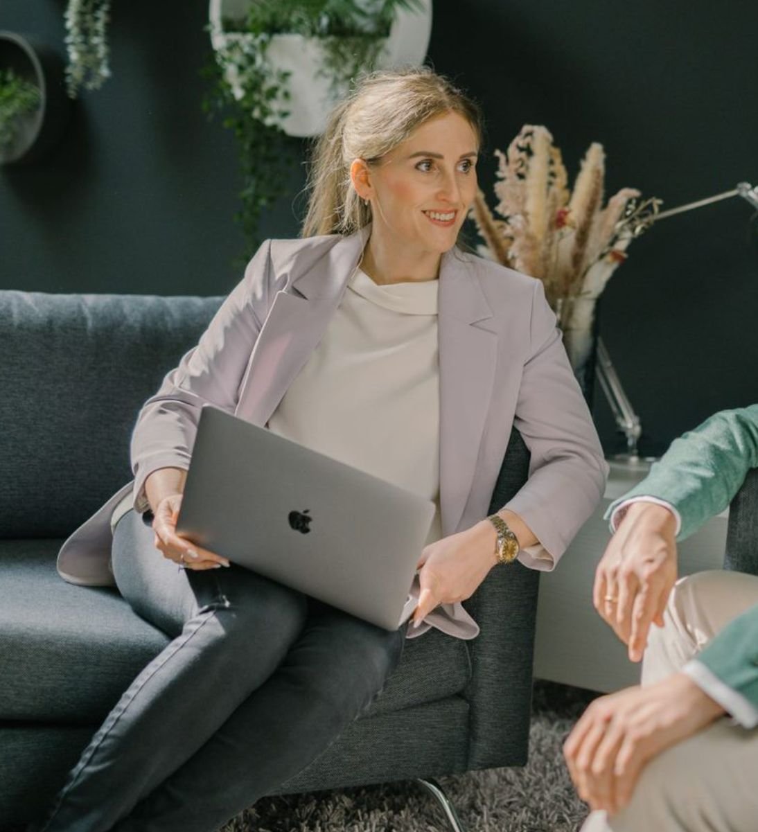 CMS & Headless Development Agentur - Frau sitzt auf dem Sofa vor ihrem PC und lächelt