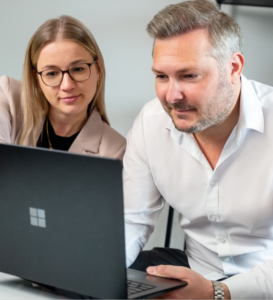 Two professionals are looking at a laptop together, discussing a solution. The image represents collaboration and consultation during CRM implementation. CRM Implementation with SUNZINET