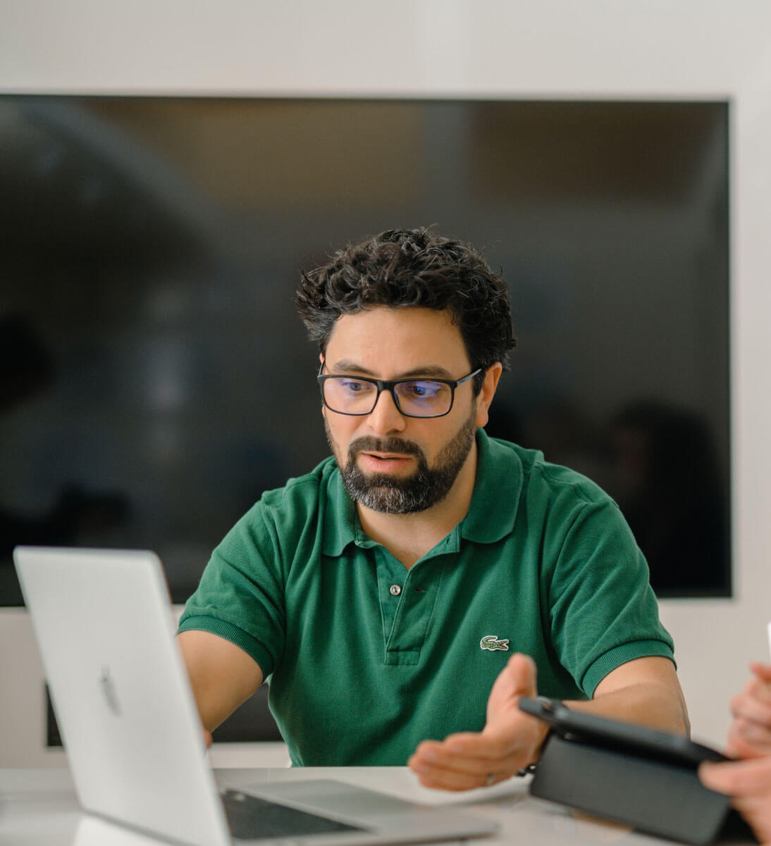 Mężczyzna siedzi przed komputerem i coś wyjaśnia