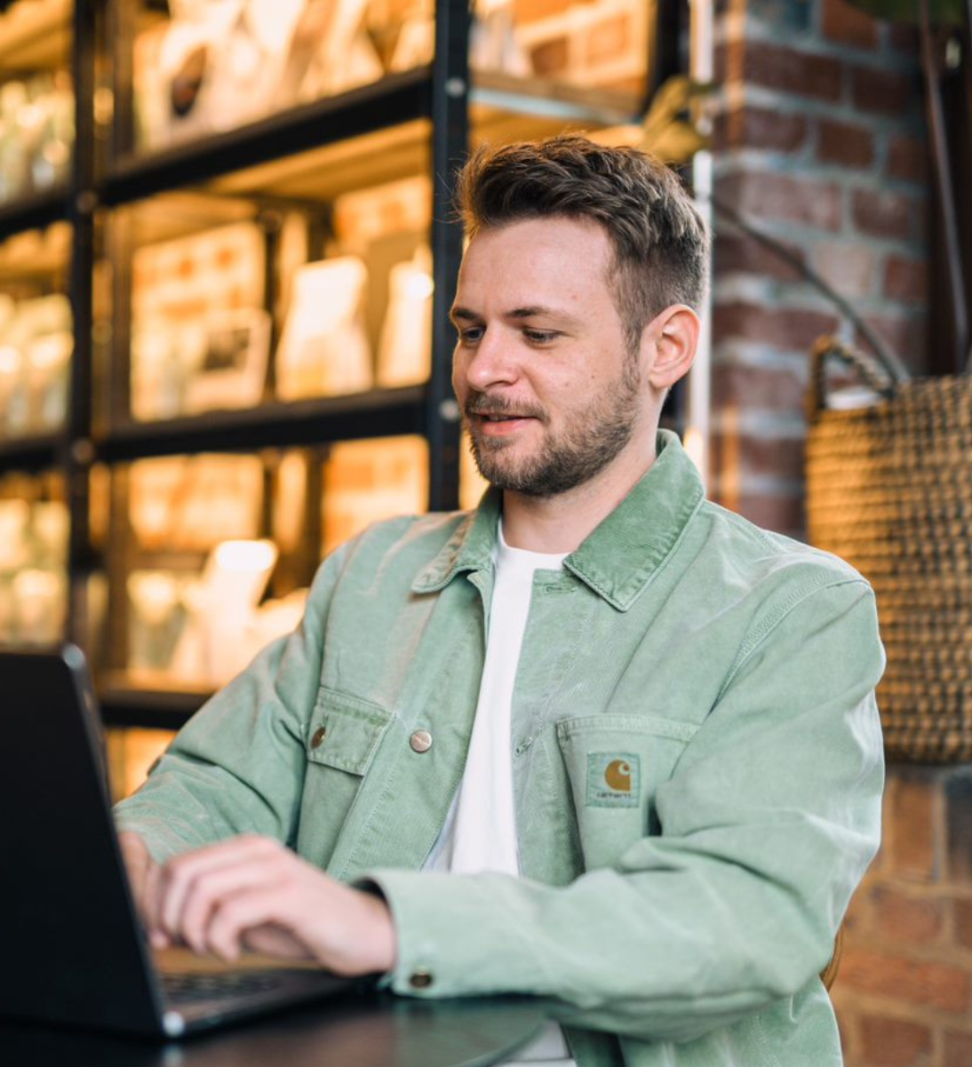 Performance Marketing Agentur - Mann sitzt vor seinem Laptop und lächelt