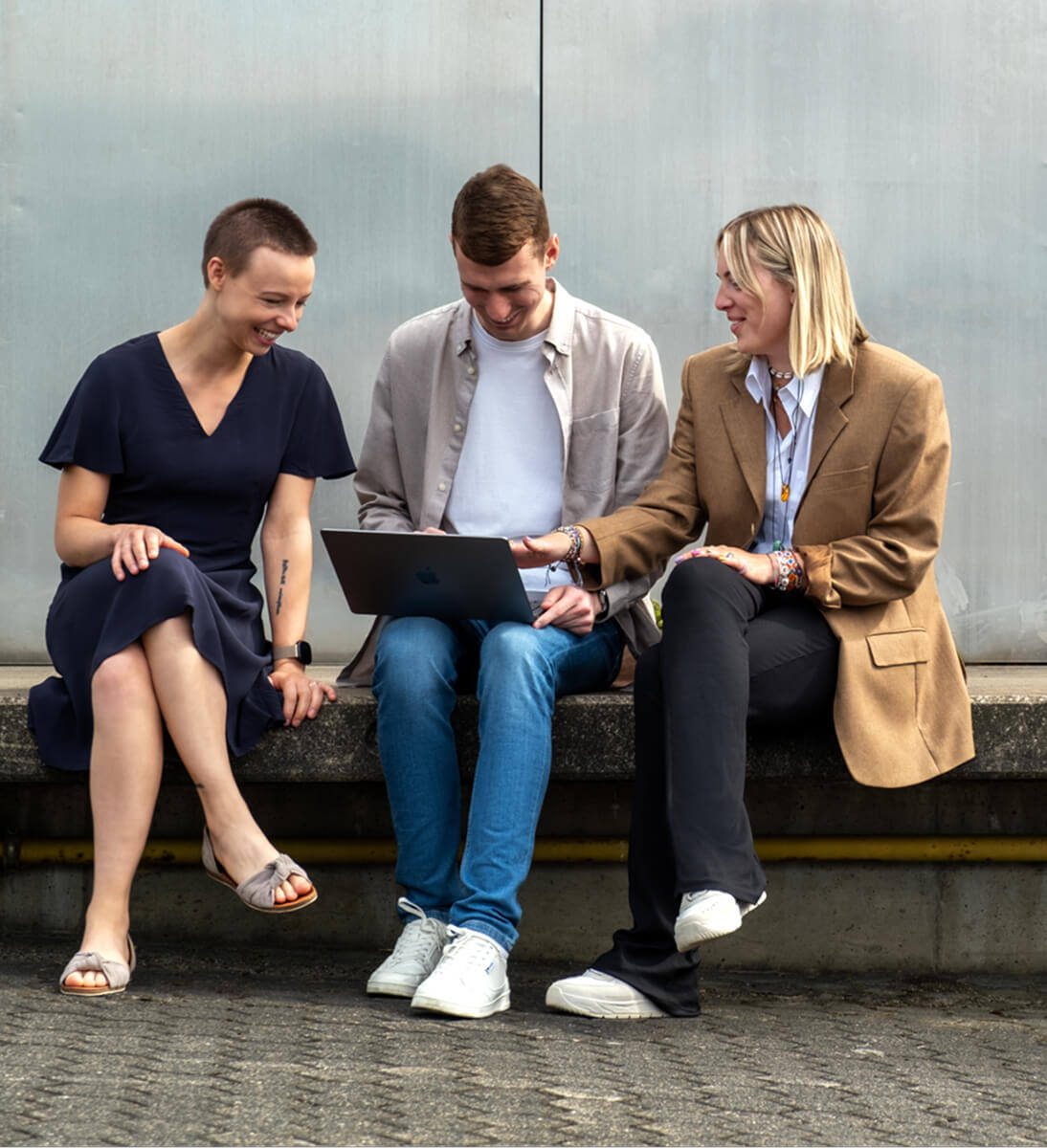 Bild einer Frau und eines Mannes in der Mitte mit einem Laptop und einer sitzenden Frau, die alle auf den Bildschirm schauen - content marketing agentur SUNZINET