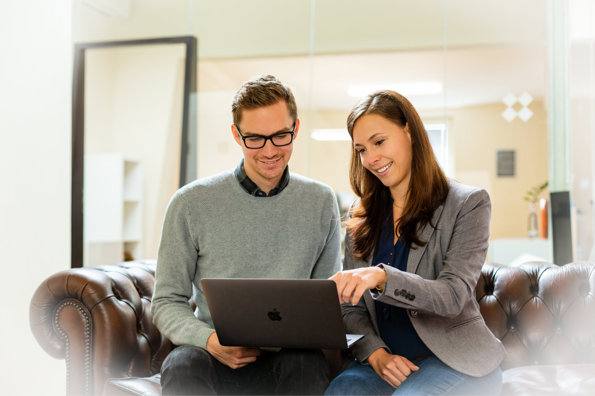 Ein Mann und eine Frau sitzen auf einer Couch und schauen gemeinsam auf einen Laptop.