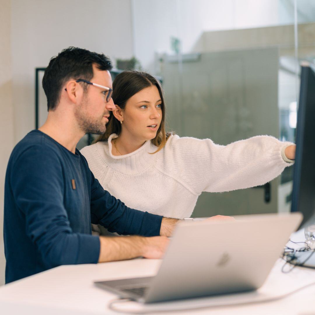 Zwei Mitarbeitende diskutieren vor einem Bildschirm - b2b leadgenerierung agentur SUNZINET