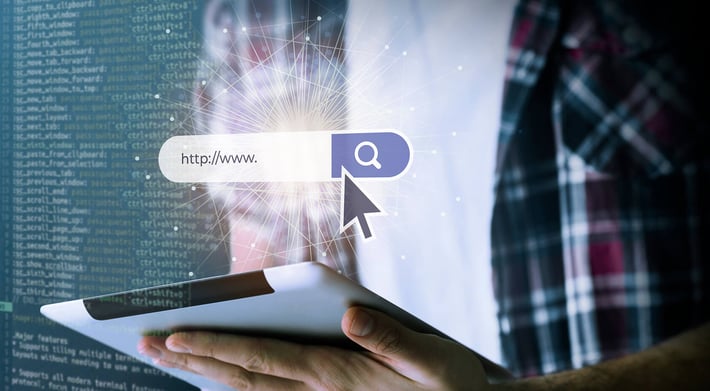 A search bar with a mouse pointer; in the background, you can see a person wearing a white T-shirt and a checked shirt, holding a tablet | AI in public sector SUNZINET